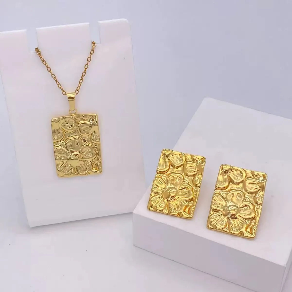 Conjunto dorado de collar con dije y aretes con flores texturizadas