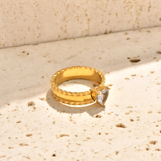 Anillo dorado con trenzado y piedra de corazón