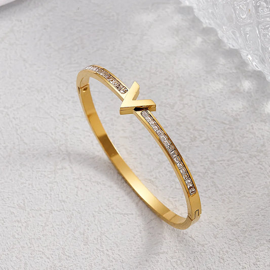 Pulsera dorada con V al centro y piedras de incrustación